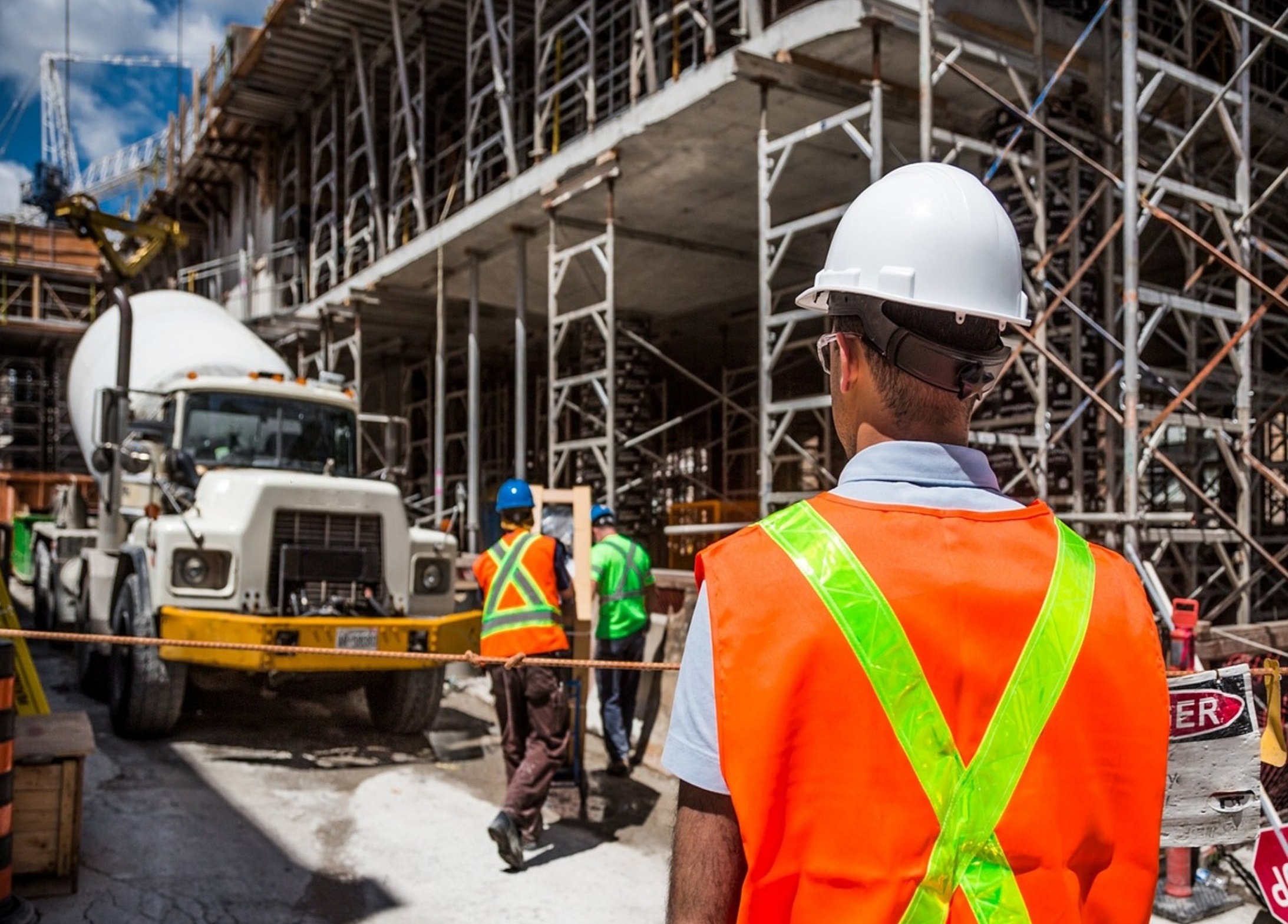 A man wearing construction PPE is observing the construction work.